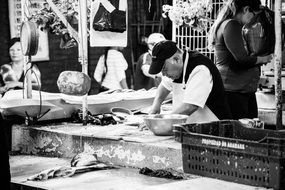 black and white photo of fish seller on the market
