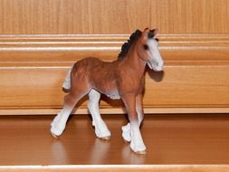 figurine of a brown horse on a wooden surface