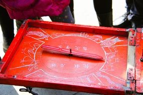 Red table with drawings of animals and pointer, asian game