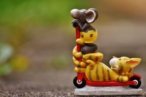 ceramic figurine of a cat with a mouse on a scooter