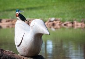 Bird on the statue of the bird in the garden
