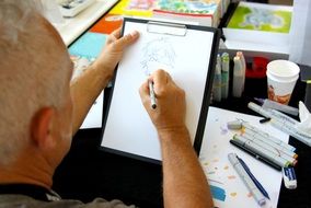 artist draws anime on a white sheet of paper