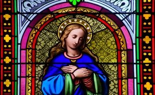 Beautiful and colorful, patterned stained glass window depicting St. Mary Magdalene