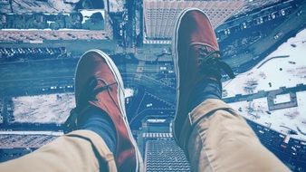 Legs hanging from a skyscraper's roof