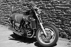 motorcycle near the stone wall in black and white background