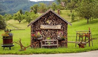 welcome, decoration with wood pile, plows and flowers at garden