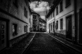 black and white photo of paved street in Erfurt, Germany with clouds in the sky