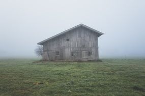 old wooden barn on a fog background