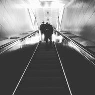 black and white photo of people climbing the escalator