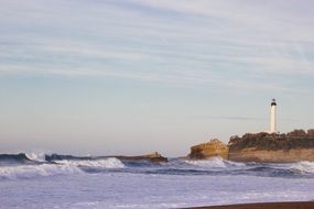 white Lighthouse on cliff at stormy Sea