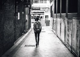 black and white photo of a young man walking along the sidewalk