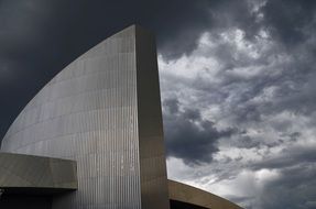 Modern Architecture, top of grey building at stormy clouds