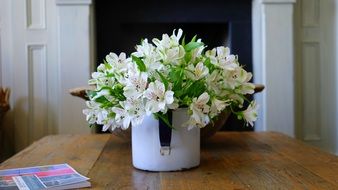 white fresia flowers in mug on wooden table