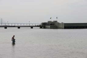 man and child walking together in water in view of Oresund Bridge, denmark