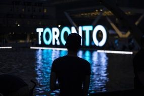 man on the background of the luminous inscription toronto