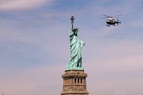 helicopter flying over the statue of liberty