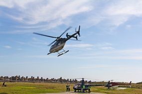 Helicopter in air and two on landing zone, cape town, south africa