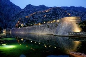 defensive fortress by the lake in night illumination