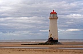 Lighthouse on sand Beach at cloudy sky