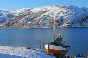 boat at the pier on the background of a snowy hill in Norway