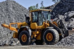 yellow bulldozer machine on the background of a mountain of stones