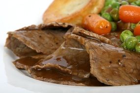 beef with sauce and vegetables on a white plate