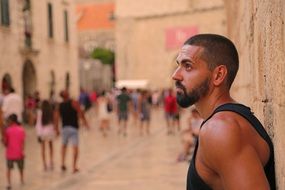 a man stands at the wall of a building on a tourist street