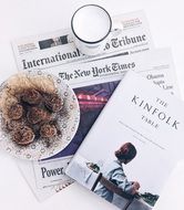 cookies on a plate, a cup of milk, newspapers and magazines on the table