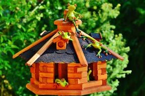 Frogs sit on the roof of a wooden house