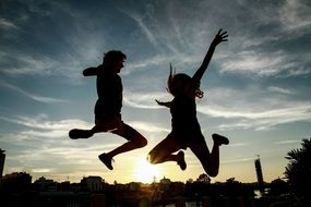 silhouettes of jumping people on a background of city sunset