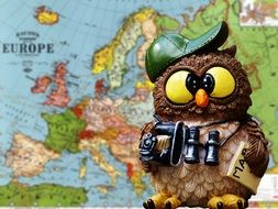 statuette of an owl on a background of a world map