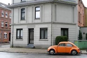orange car stands near the house
