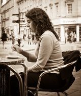 monochrome picture of young Woman sits at table in street cafe, uk, england