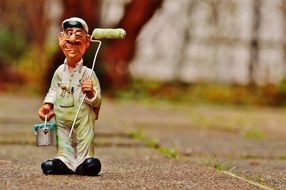statuette of a painter with a roller and a bucket of paint in the hands of
