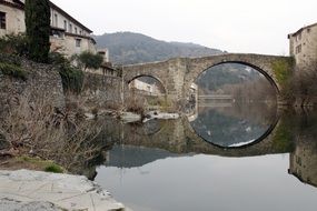 reflection of a stone bridge in a river in a french province