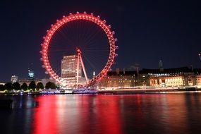 distant view of a ferris wheel in london in red night illumination