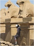 man sits beneath ancient sculptures, Egypt, Luxor, Karnak temple