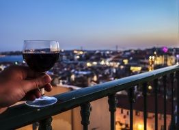 a glass of red wine on the balcony grate in the background of the panorama of Lisbon