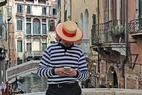 Man in hat with the phone near the water channel in Venice, Italy