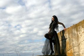 goth girl in black near stone wall