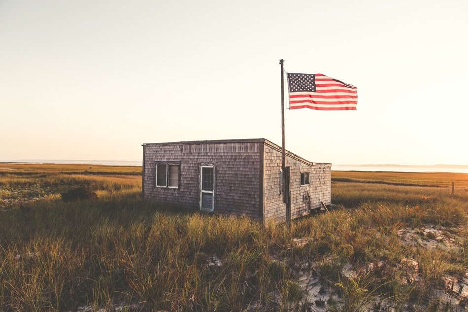 American flag near the house on the field on beautiful landscape