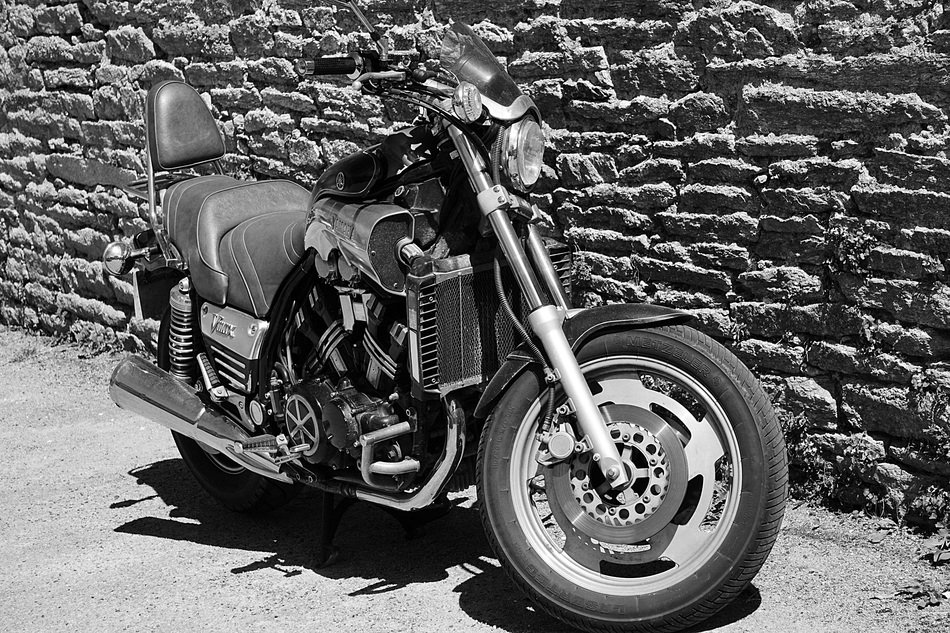 motorcycle near the stone wall in black and white background
