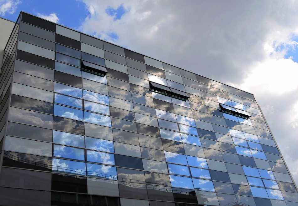 clouds are reflected in the windows of the mirror facade
