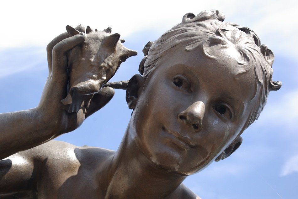 child listens to the sea shell sculpture