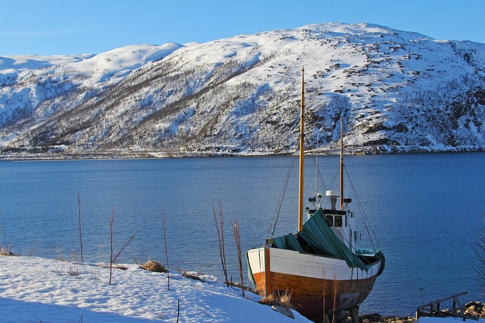 boat at the pier on the background of a snowy hill in Norway