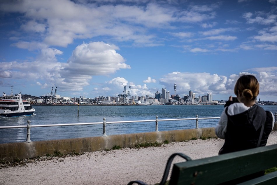 young girl sits on bench in view of harbor