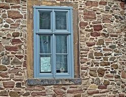 Old stone house wall with wooden window