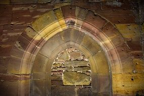 arch in wall of Gothic Building closed with wild stone, france