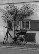 Black and white photo of the bike near the house wall