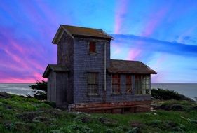 abandoned building by the sea on a background of colorful sunset